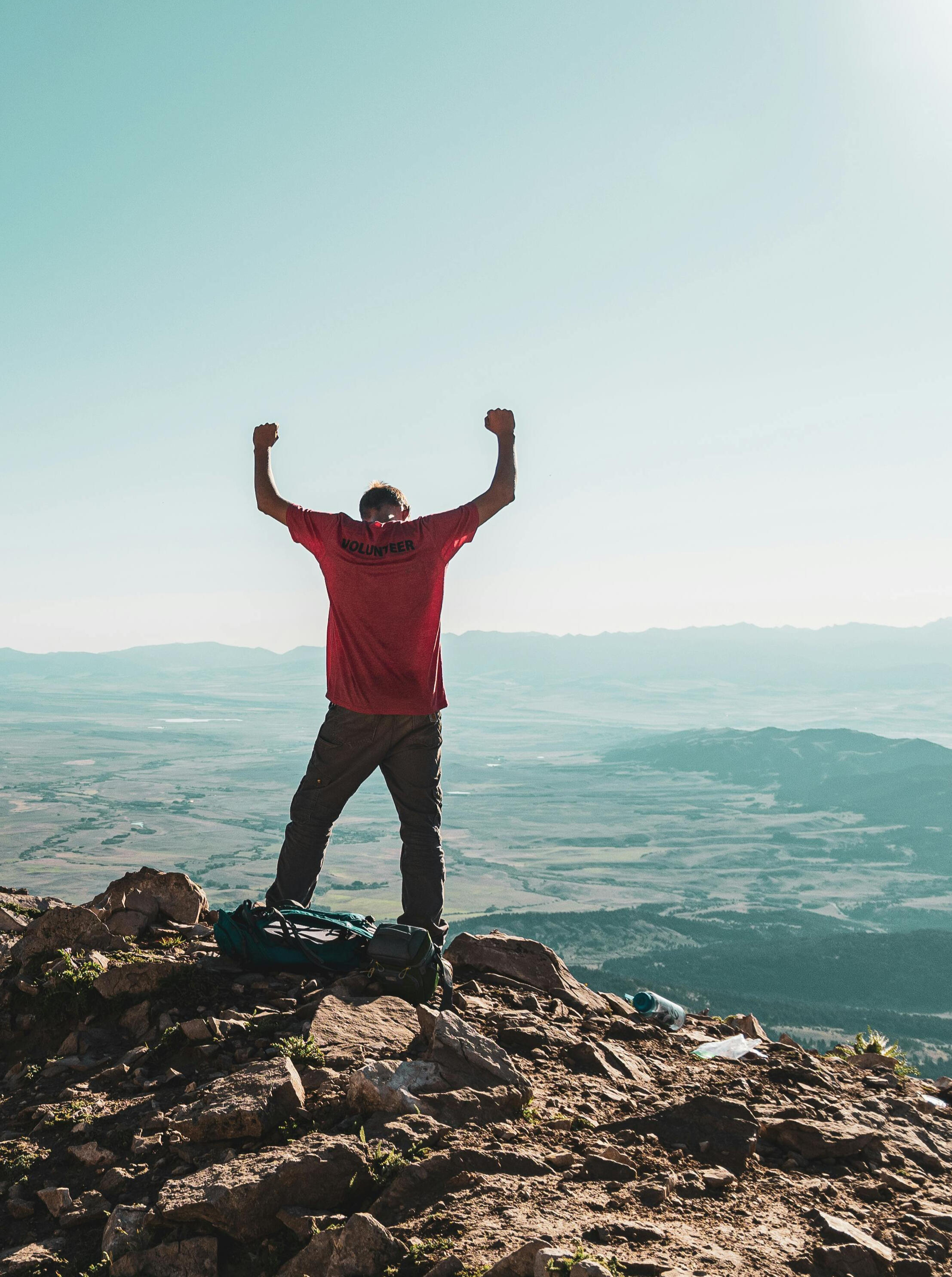 Man on a mountain top raising hands